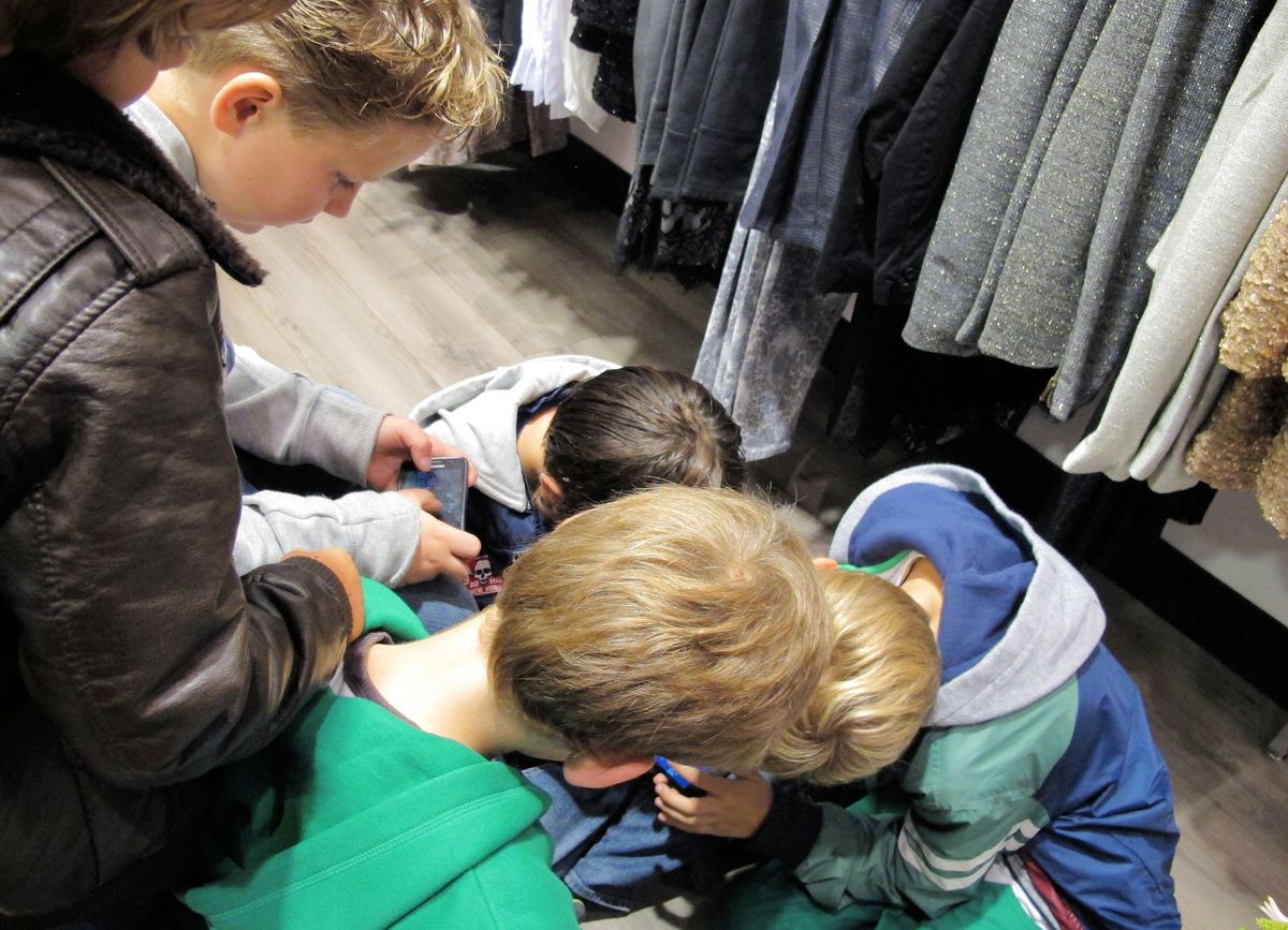 Tijdens het shoppen van de moeders vermaken de kinderen zich met spelletjes op mobiele telefoons