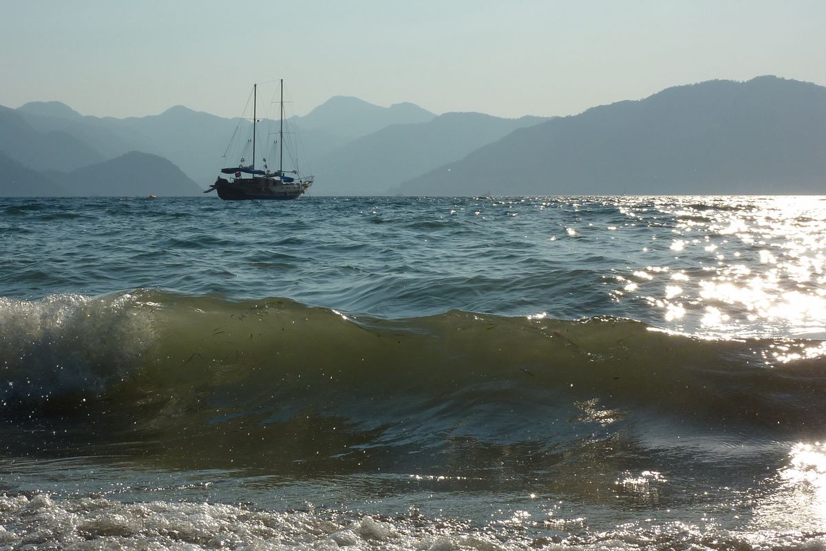 Rustige golven aan de oever bij Marmaris, Turkije. In de verte een schip.